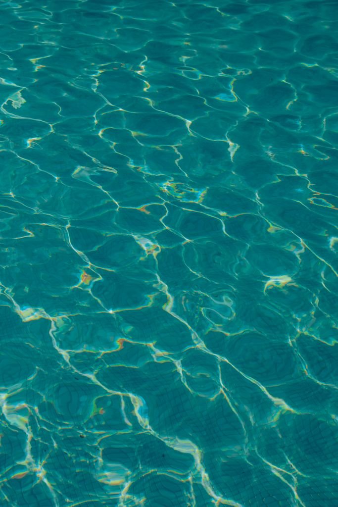 Captivating pattern of sunlit teal water ripple highlights, evoking tranquility and serenity.